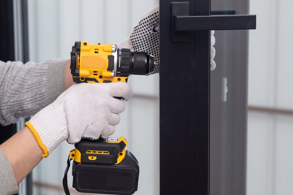 Installer fixing door hardware to a metal door with screwdriver